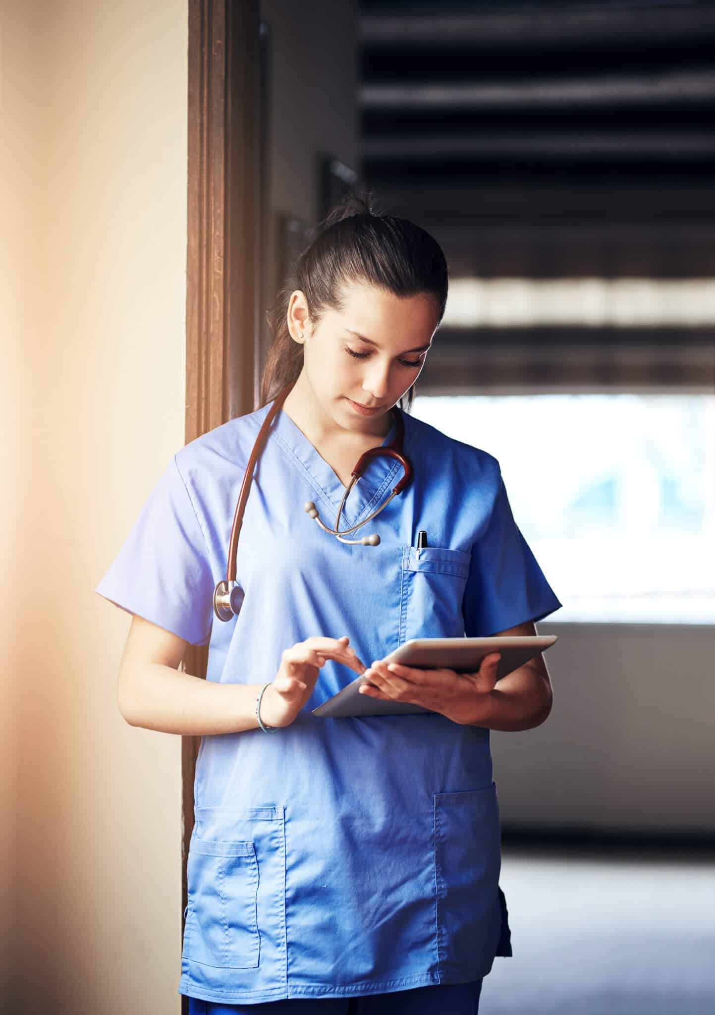 Specialist on tablet in hospital hallway.